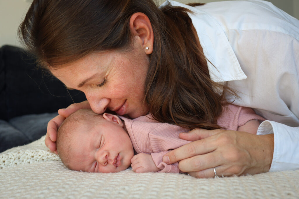 Neugeborenen Shooting Muenchen - Mutter kuschelt sich an ihr schlafendes Baby Mutter kuschelt sich an ihr schlafendes Baby